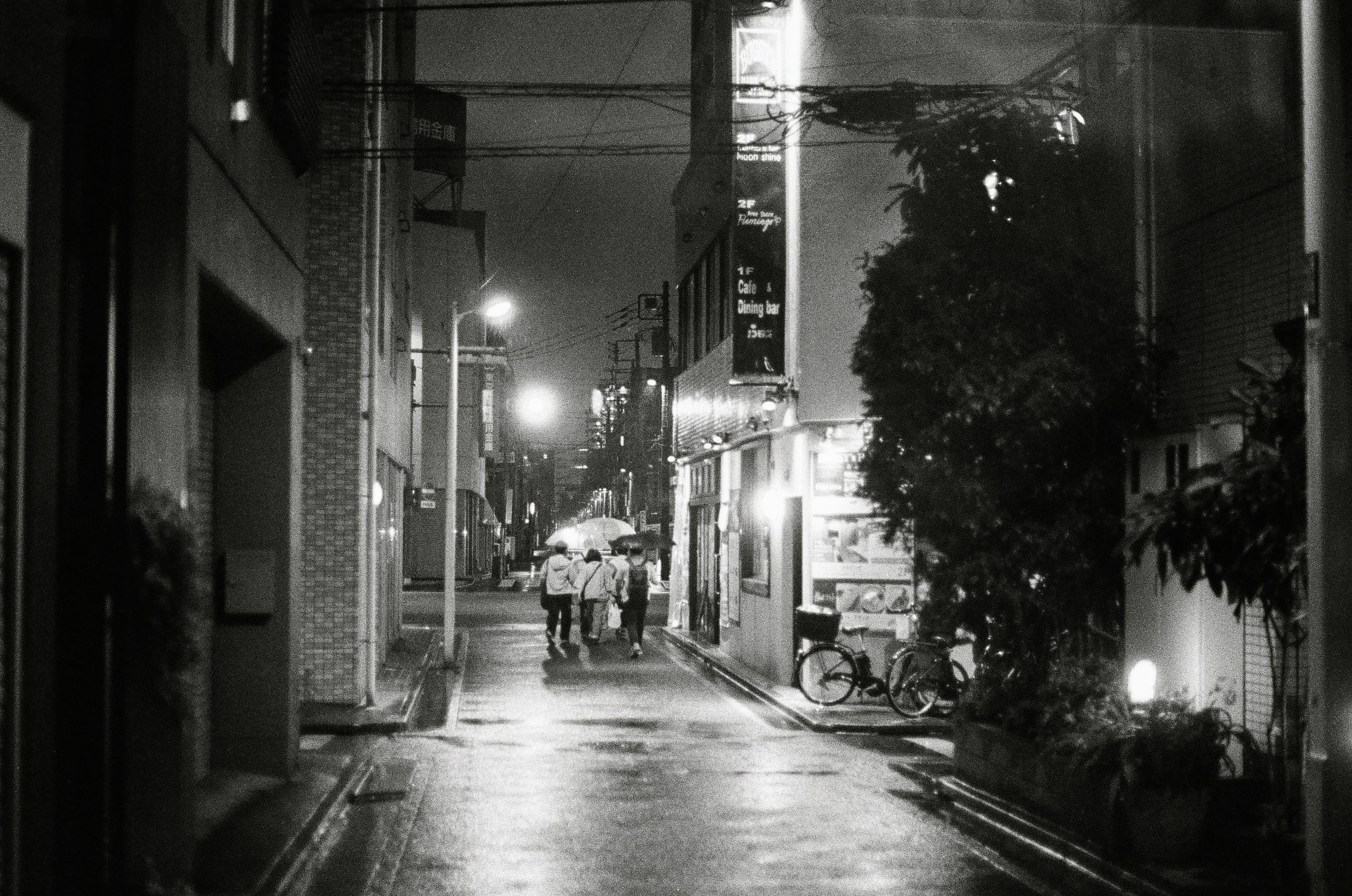 A family huddle under and umbrella running to find shelter in a sudden nightime downpour.